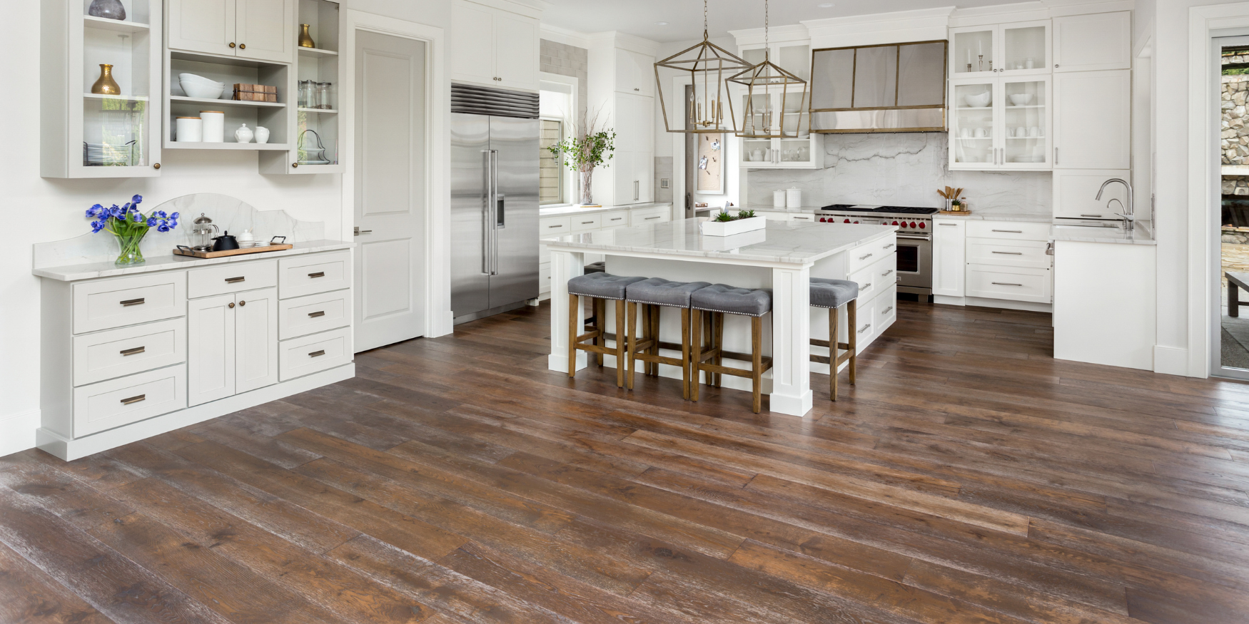 A white kitchen with wood floors and white cabinets