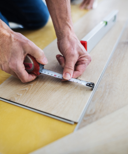 A man measuring a piece of wood with a tape measure