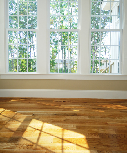 A room with three windows and a wooden floor